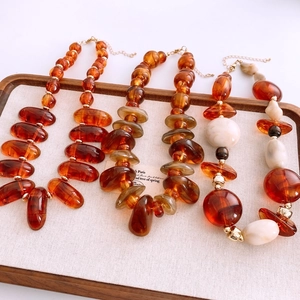Detail of amber acrylic beaded necklaces with gold metal spacers in four styles