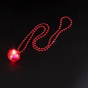 Detailed view of red glowing heart pendant necklace with beaded chain on black backdrop
