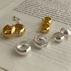 Macro shot of 925 silver and gold chunky hoop earrings on vintage book paper texture