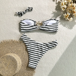 Flat lay of black and white striped bikini with gold starfish buckle and matching scrunchie