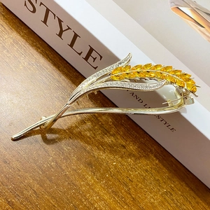 Elegant gold crystal wheat ear hair clip for women displayed on a rustic wooden background