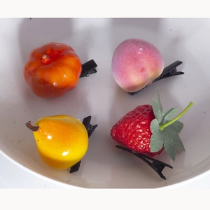 Close-up of 4-piece set 3D fruit hair clips with strawberry and peach in a white bowl