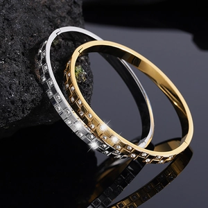 Macro detail of gold and silver waffle pattern diamond-set open bangles on black stone