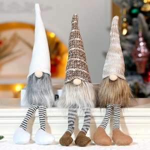 Close-up of three long-legged Christmas gnomes sitting in a warm festive setting