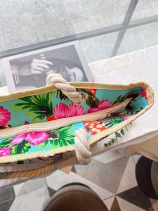 Detail of tropical floral canvas tote with beige zipper closure and hemp rope handle