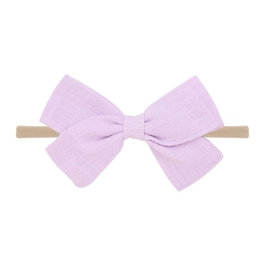 Close-up of a light purple linen bow on a soft nude nylon headband for infants