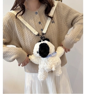 Detail of cute black and white plush dog backpack with blue plaid scarf and beige strap