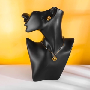 Golden clover jewelry set with pearls on necklace and earrings worn on a black bust