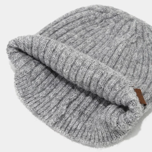 Close-up of grey ribbed knit beanie showing thick wool texture and brown leather label