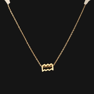 Macro shot of gold Aquarius zodiac pendant with fine chain on a black background