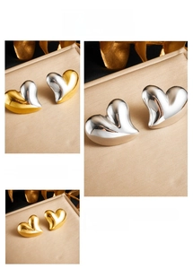 Detailed views of heart-shaped earrings in gold and silver finishes on satin fabric