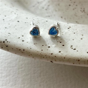 Macro shot of blue heart-shaped cubic zirconia studs on a ceramic tray