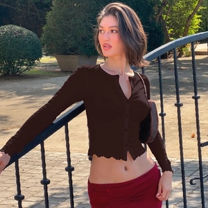 Photo en extérieur d'un cardigan court marron ajusté à boutons et manches longues
