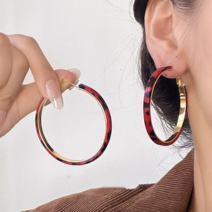 Macro detail of large leopard print hoop earrings with red and black resin texture