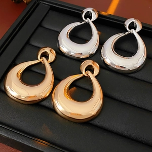 Detail of gold and silver teardrop earrings on black display tray with metallic finish