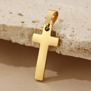 Macro shot of polished gold stainless steel cross pendant on natural stone texture