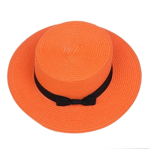 Top view showing the intricate weave of the orange wide brim straw hat with a black bow