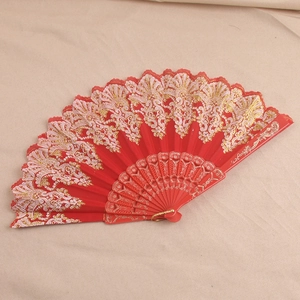 Detail of red lace folding fan featuring intricate gold patterns and plastic carved ribs