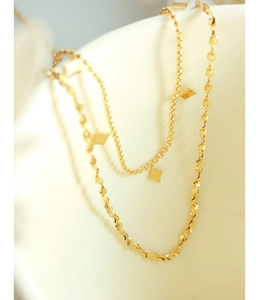 Detail of double-layer gold chain necklace with geometric diamond-shaped pendants