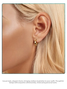 Close-up of a minimalist gold hoop earring worn by a model for a chic luxury look