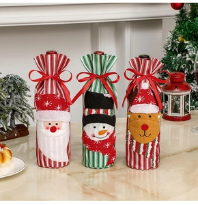 Detailed view of three knitted Christmas wine bottle covers with Santa, snowman and reindeer