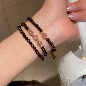 Close-up of layered garnet and strawberry quartz beaded bracelets with gold accents on wrist