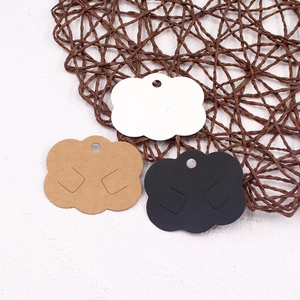 Cloud-shaped paper jewelry display cards in white, brown, and black on a woven mat