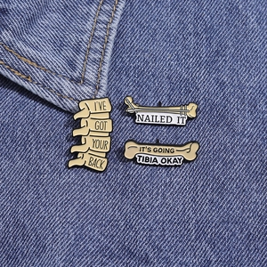 Set of anatomical enamel pins with medical puns on blue denim fabric background