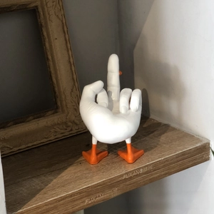 Detailed close-up of a funny duck middle finger resin figurine on a wooden shelf