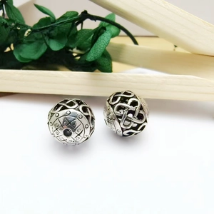 Macro shot of silver hollow metal beads with Celtic knot patterns for jewelry making