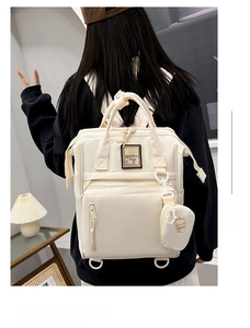 Detail view of large-capacity beige nylon diaper bag with multiple zippers and round pouch