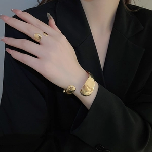 Detail of minimalist gold droplet open bracelet and ring set on black fabric