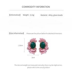 Detailed view of pink floral earrings with green oval glass beads and alloy texture