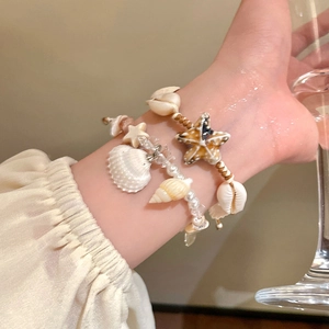 Detail of seashell and starfish bracelets on hand with a warm beach holiday vibe