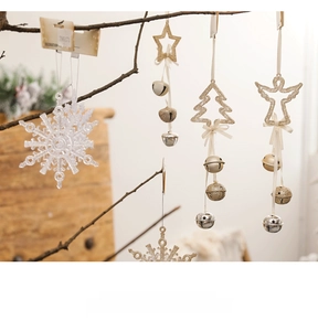 Golden Christmas star and snowflake ornaments with bells hanging on rustic tree branches