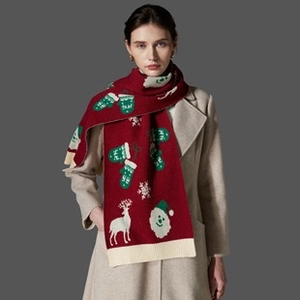 Detailed knit pattern showing festive reindeer and snowflake motifs on red Christmas scarf