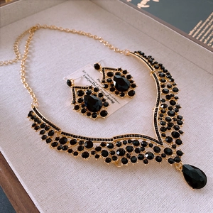 Vue détaillée du collier doré et boucles d'oreilles goutte avec cristaux noirs