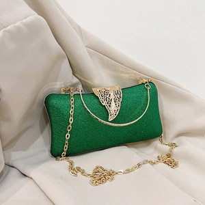 Elegant green evening clutch bag with gold leaf clasp and chain strap on beige fabric
