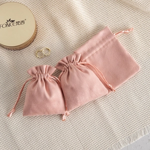 Detailed view of pink velvet drawstring jewelry pouches on a textured fabric background
