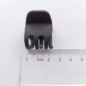 Detailed macro view of small 3.5cm matte black claw clip with ruler measuring size