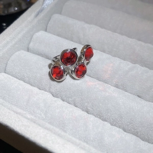Macro shot of silver ring featuring a cluster of four faceted red gemstones on grey velvet