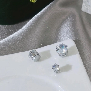 Detailed close-up of three sparkling silver zircon magnetic earrings on a white ceramic tray