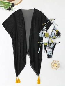 Flat lay of abstract print bikini set with black mesh cover-up and tassel details
