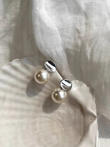 Detailed close-up of French style S925 silver pearl earrings resting on a white shell