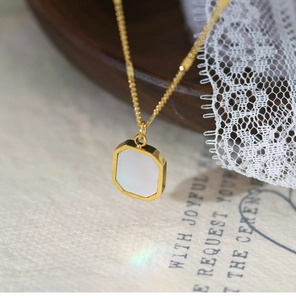 Detail of golden octagon pendant with white mother of pearl inlay on fine link chain