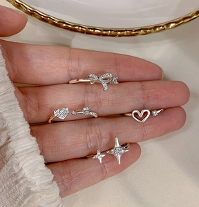 Close-up of sparkling heart and bow knot rings with star details on a hand