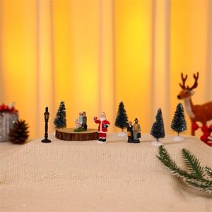 Miniature Christmas set with Santa Claus, street lamps and trees on a beige linen base
