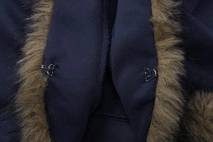 Detailed close-up of dark blue fabric with brown fur collar and silver metal hook closures