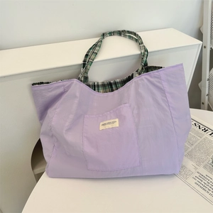 Gros plan du sac fourre-tout réversible en toile violette avec doublure à carreaux.