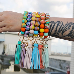 Close-up of colorful silicone bead wristlet keychains with tassels on a tattooed wrist
